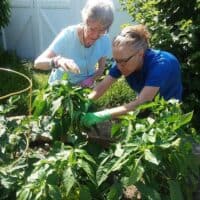 Resident in Memory Care gardens with the help of a caregiver