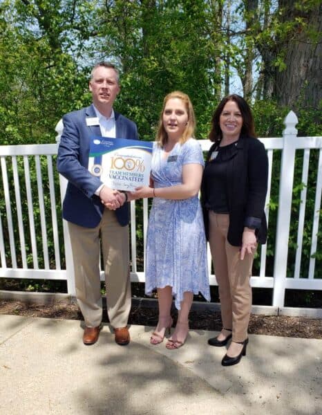 Sales and Marketing, Brandon Smeltzer, presents Executive Operations Officer, Morgan Burroughs, with certification of 100% Vaccination