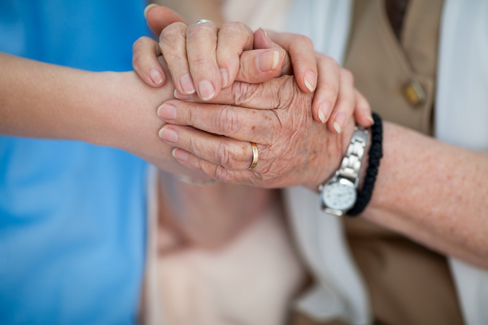 Senior woman and her nurse hold hands