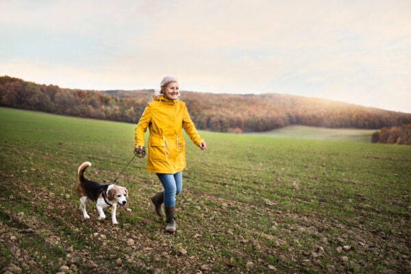 A senior woman walks her dog outdoors