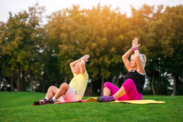 A senior couple practices yoga outdoors.