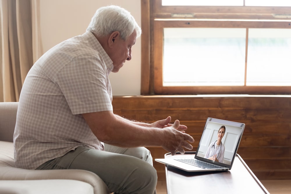 A senior man uses telehealth services to video call a doctor