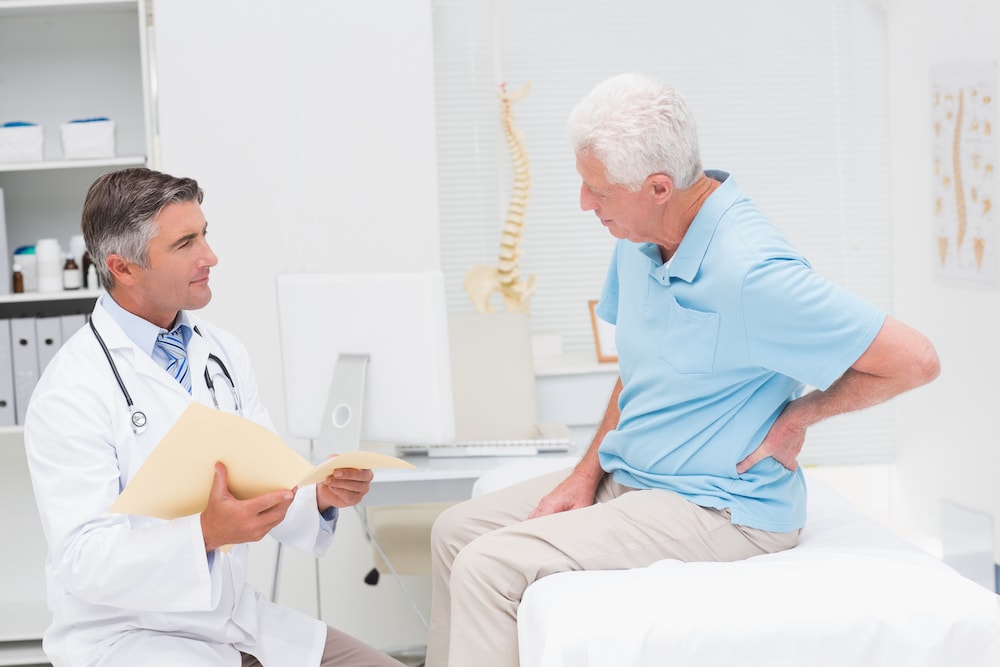 A senior man with back pain visiting his doctor