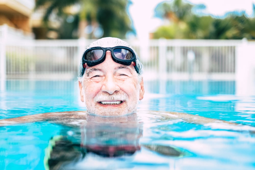 A senior man swimming at an outdoor pool