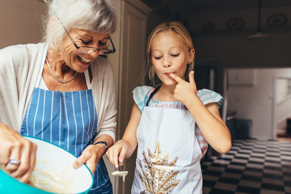 A senior woman and her granddaughter bake together