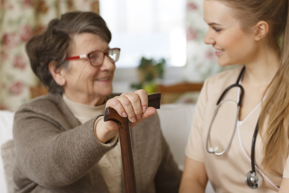 A senior with a cane talking to a nurse