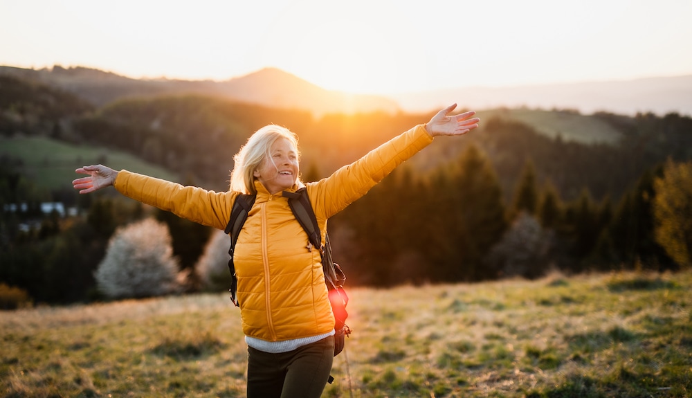 A senior woman smiles out on a morning hike