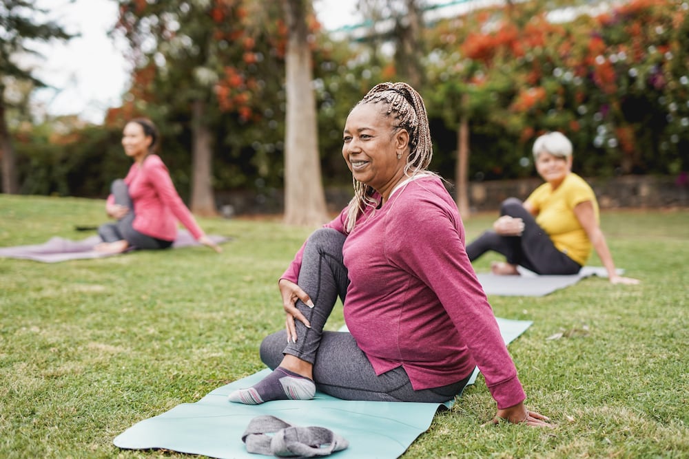 A group of senior women practice yoga outdoors