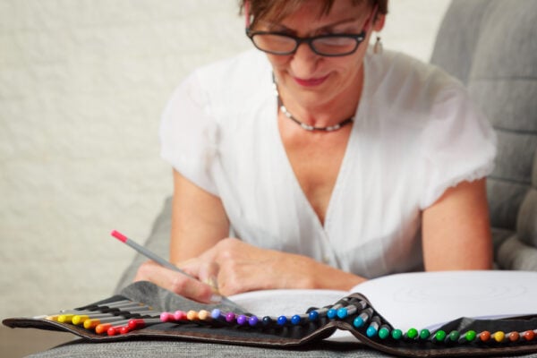 A senior woman colors in an adult coloring book