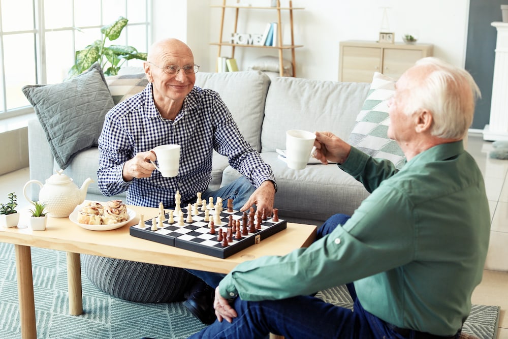 Two senior friends play chess together