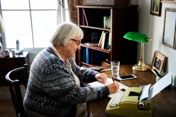 A senior woman sitting at her desk and writing in a journal