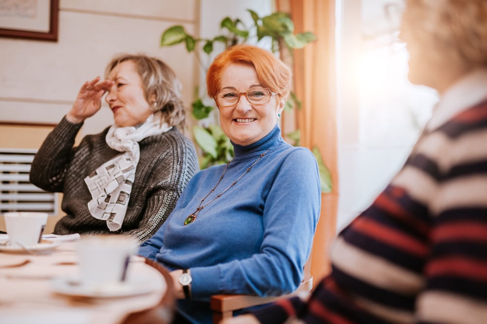 Three senior women drink tea and socialize together