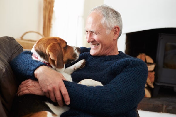 A smiling senior man relaxes at home with his dog