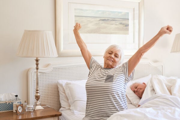 A happy senior woman stretching and yawning as she wakes up