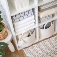 Folded linens in baskets put away in a storage shelf