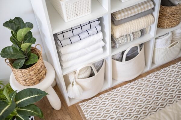 Folded linens in baskets put away in a storage shelf