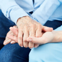 A senior woman holding hands with her caregiver