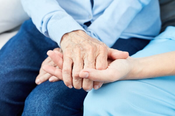 A senior woman holding hands with her caregiver