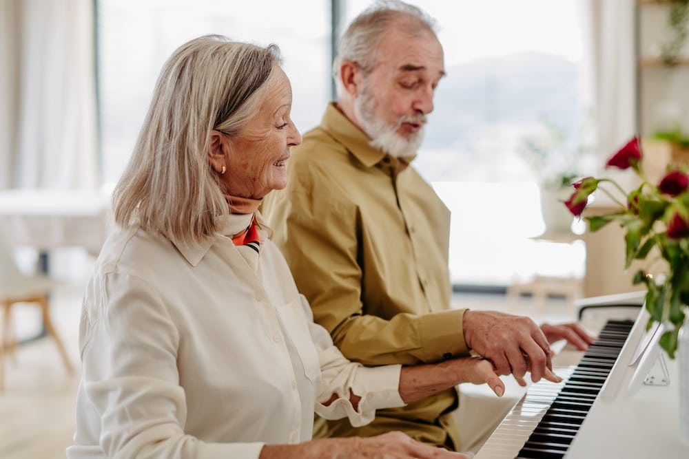 A senior couple plays the piano together