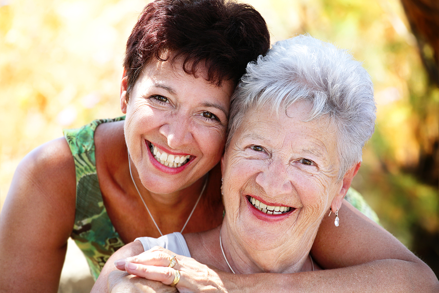 close up portrait of a beautiful senior mother and daughter smiling at the camera