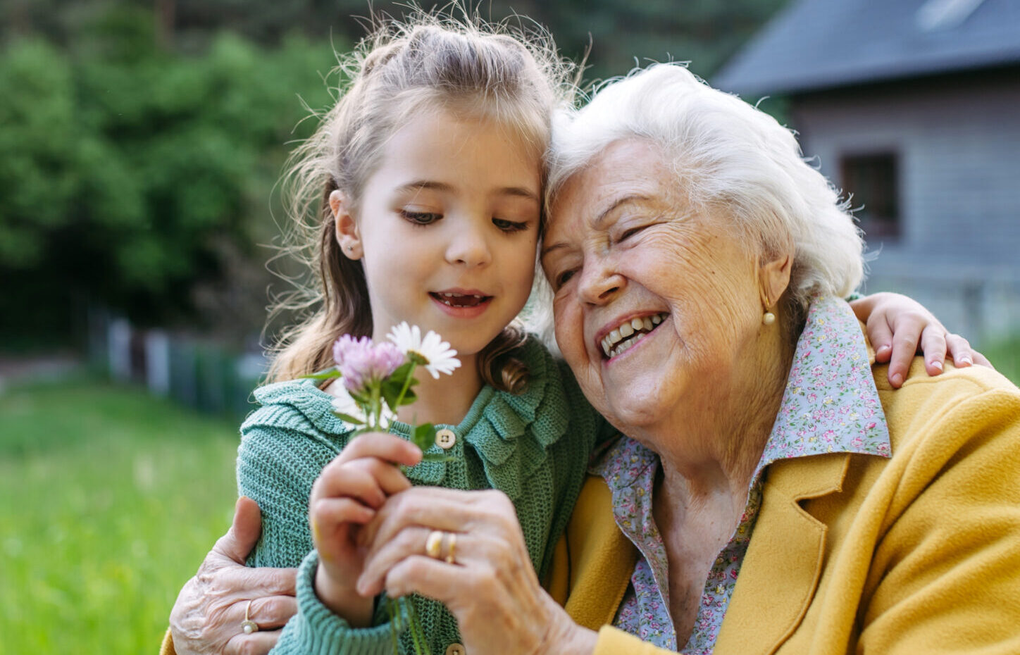 Granddaughter spending time with elderly grandma, picking widlflowers. Senior lady in wheelchair spending time in nature. Weekend in cottage.