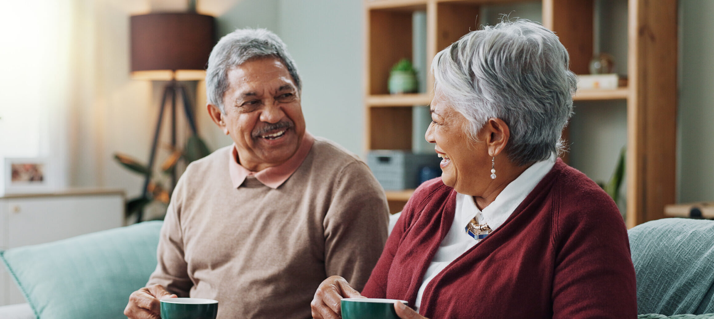 Living room, relax and elderly couple with coffee for love, bonding and funny conversation. Senior people, smile and happy with drink for morning discussion, communication and peace in retirement