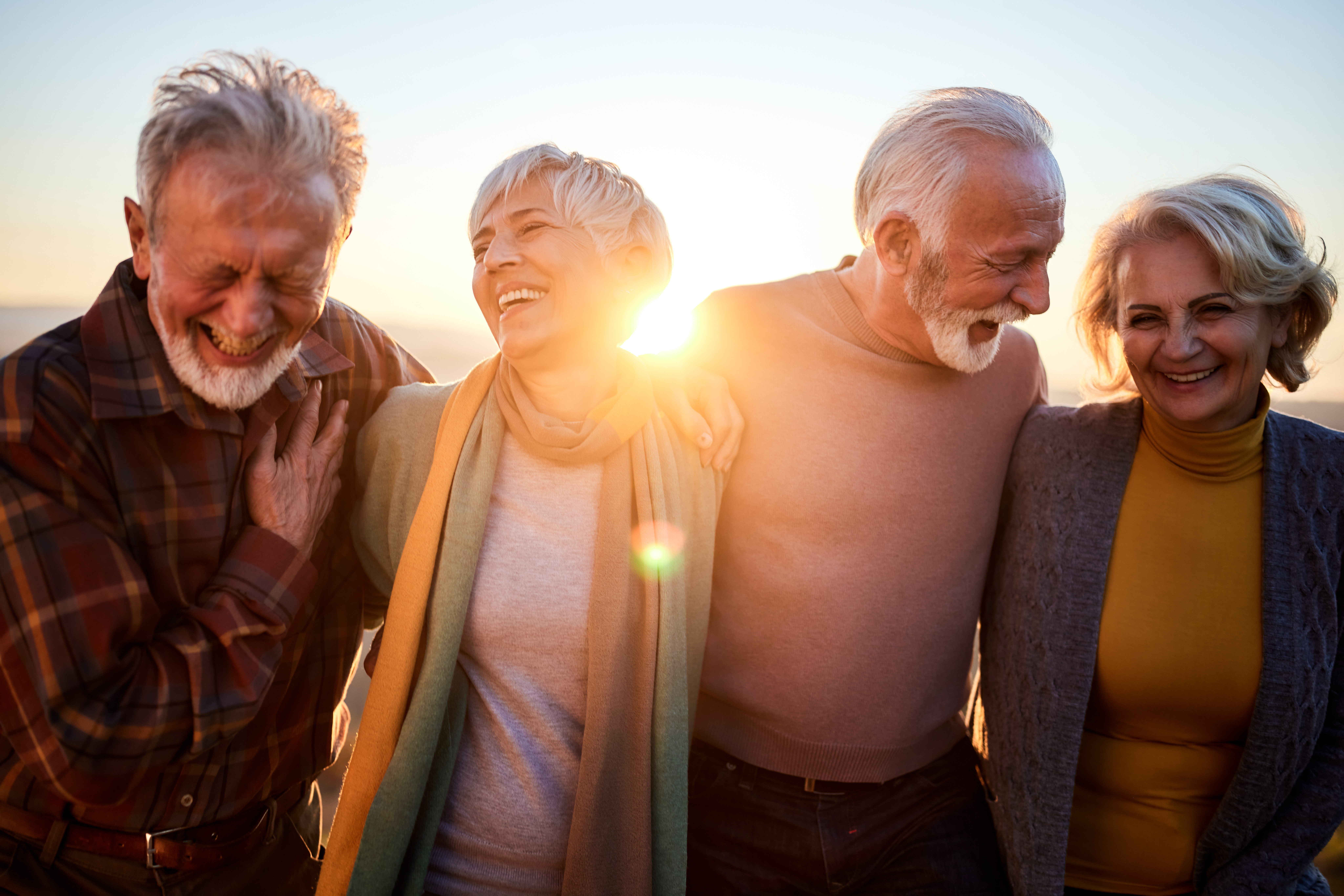 A group of senior friends, laughing in the sunset