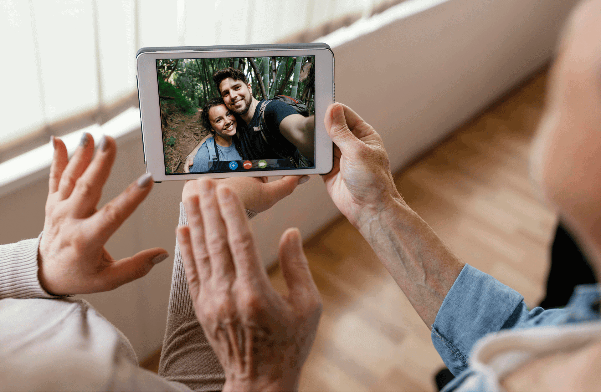 senior holding a tablet talking to family members