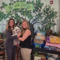 women holding white dog