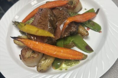 Beef with roasted carrots, scallops, fingerling potatoes, and snap peas on a white plate