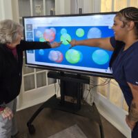 Magnolias of Lancaster resident Janice Hannum and Resident Wellness Associate Arianna Washington use iN2L technology at the senior living community.
