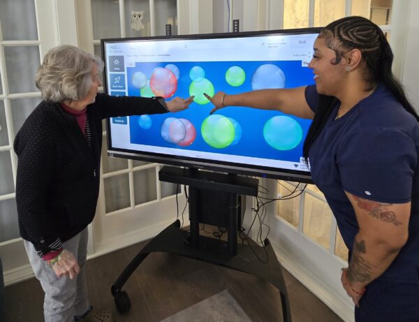 Magnolias of Lancaster resident Janice Hannum and Resident Wellness Associate Arianna Washington use iN2L technology at the senior living community.