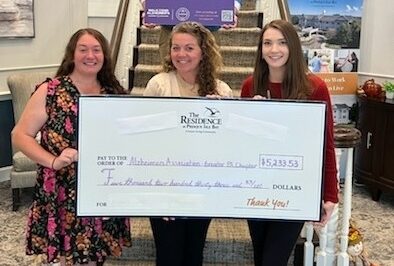 Three women holding a large check smiling
