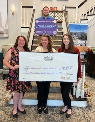 Three women holding a large check smiling