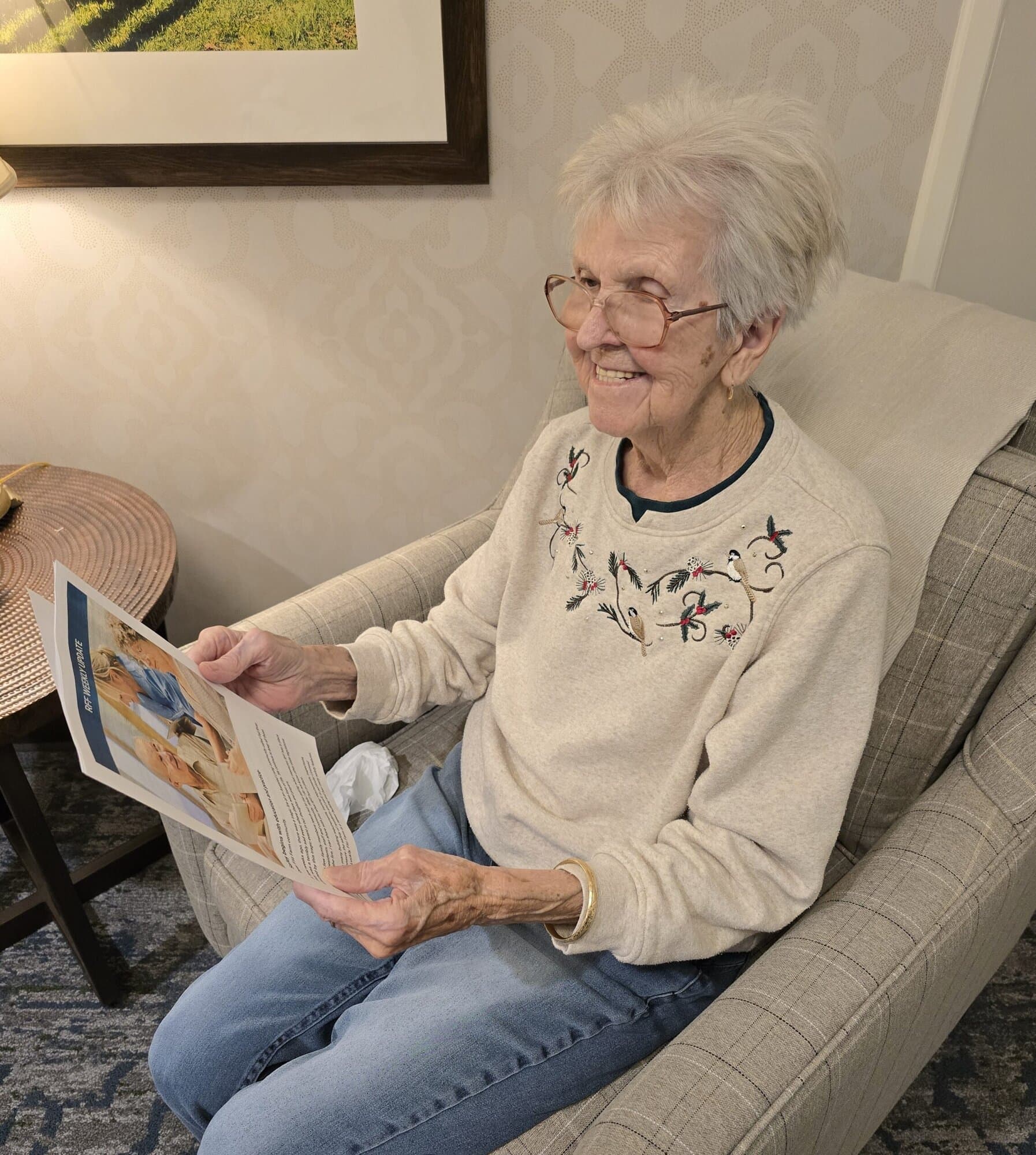 Elderly woman smiling while reading a "Weekly Update"