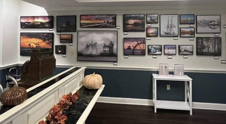 A curated gallery wall at The Residence at Presque Isle Bay featuring framed photographs of local landscapes, sailboats, and sunsets.