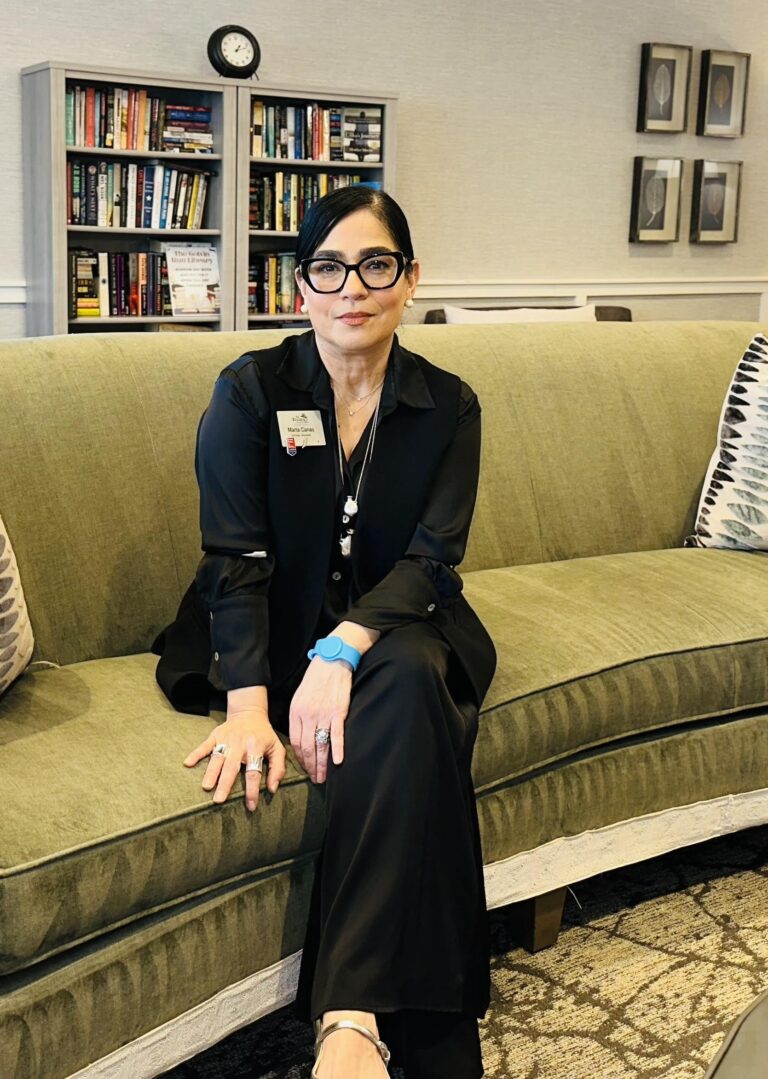 Marta Canas Granados, lead for senior art classes at The Residence at Colvin Run, is sitting on a green sofa.