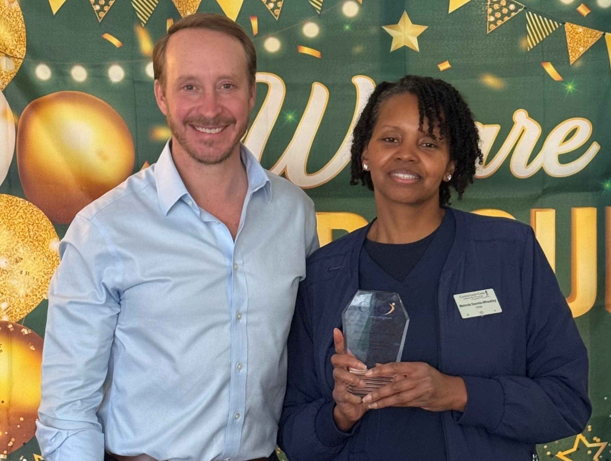 Melinda Dennis-Wheatley, an exceptional caregiver at Candle Light Cove, holding her 2025 National Ceca Award trophy next to Ceca President Nate Hamme.