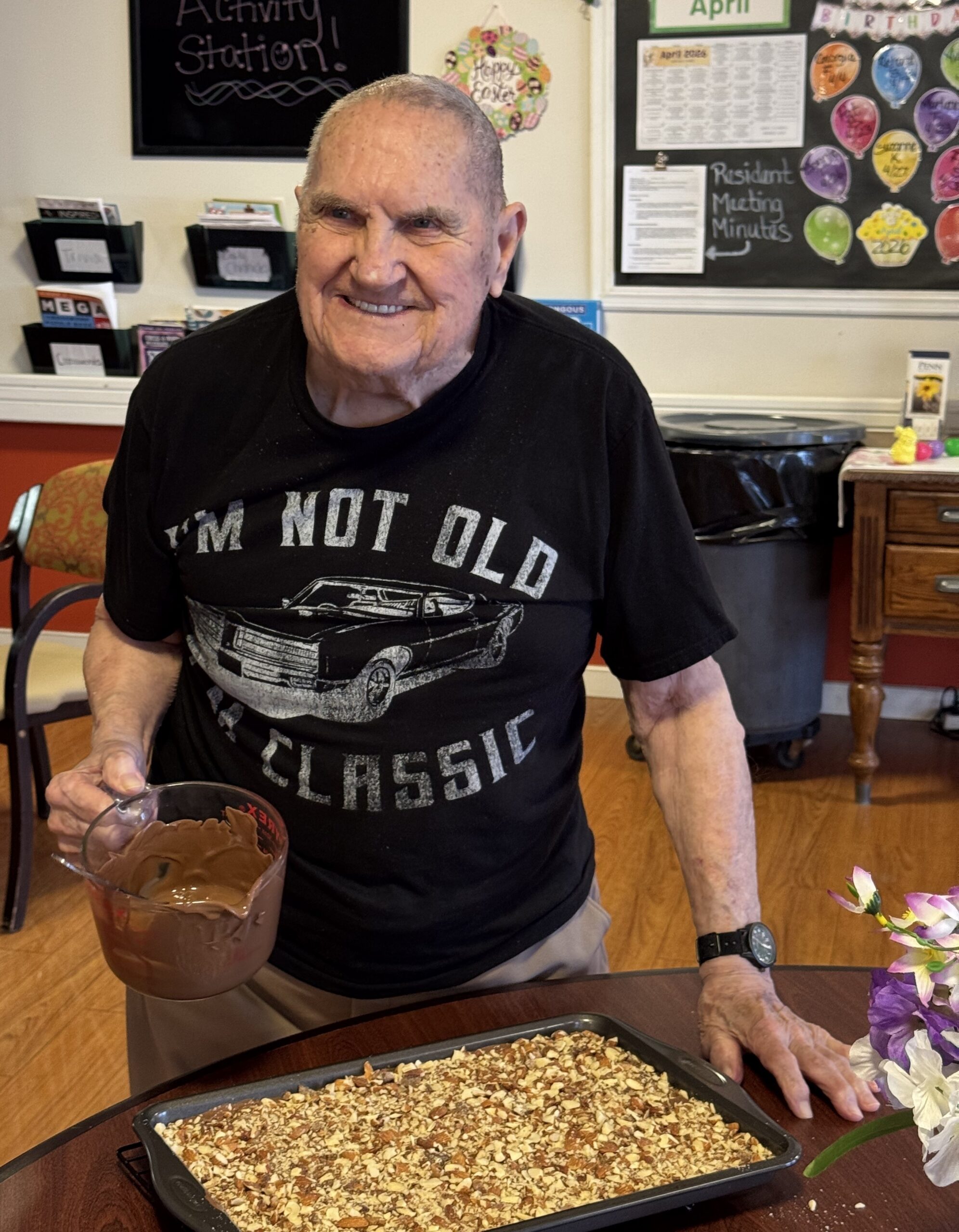 Senior living Candy Man Elvin Norby smiling with a tray of his famous homemade toffee at Newhaven Court at Lindwood.